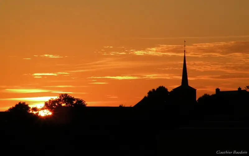 Photo du clocher de l'église de Noville lors d'un coucher de soleil estival